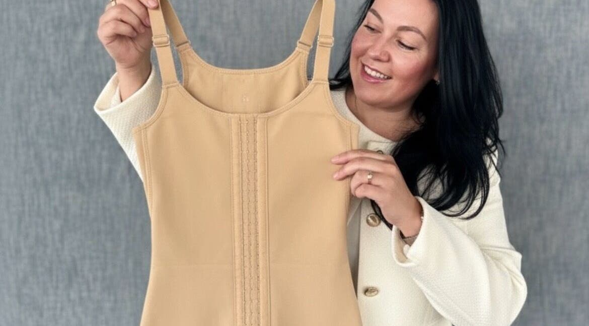 Smiling individual holding shapewear at BCM AESTHETICS Mobile Service Brazilian Lymphatic Drainage in London, England, GB.