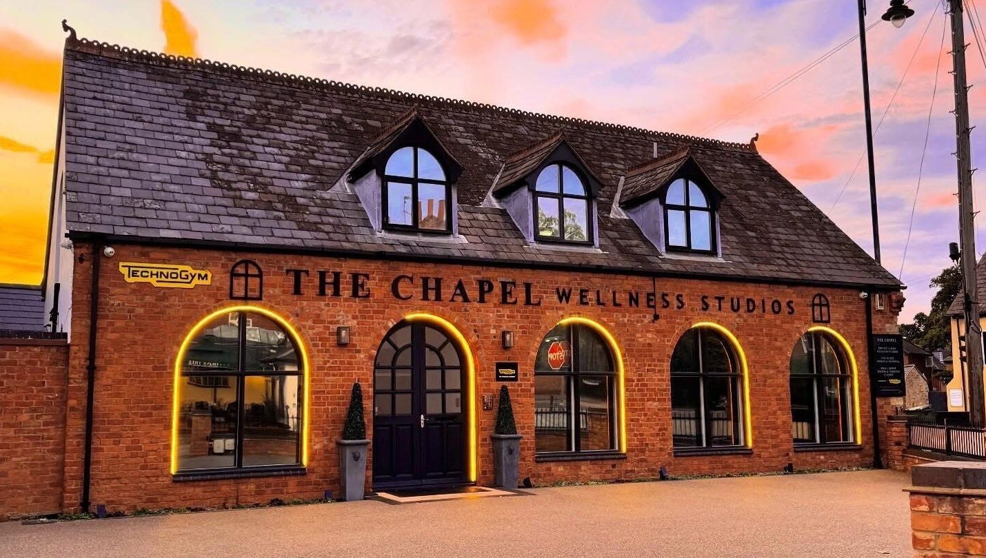 AP Beauty MK venue in Towcester, England, GB. Brick facade with arched windows and Technogym sign at sunset.