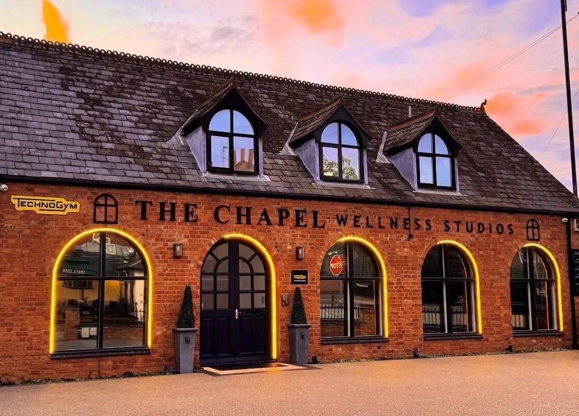 AP Beauty MK venue in Towcester, England, GB. Brick facade with arched windows and Technogym sign at sunset.