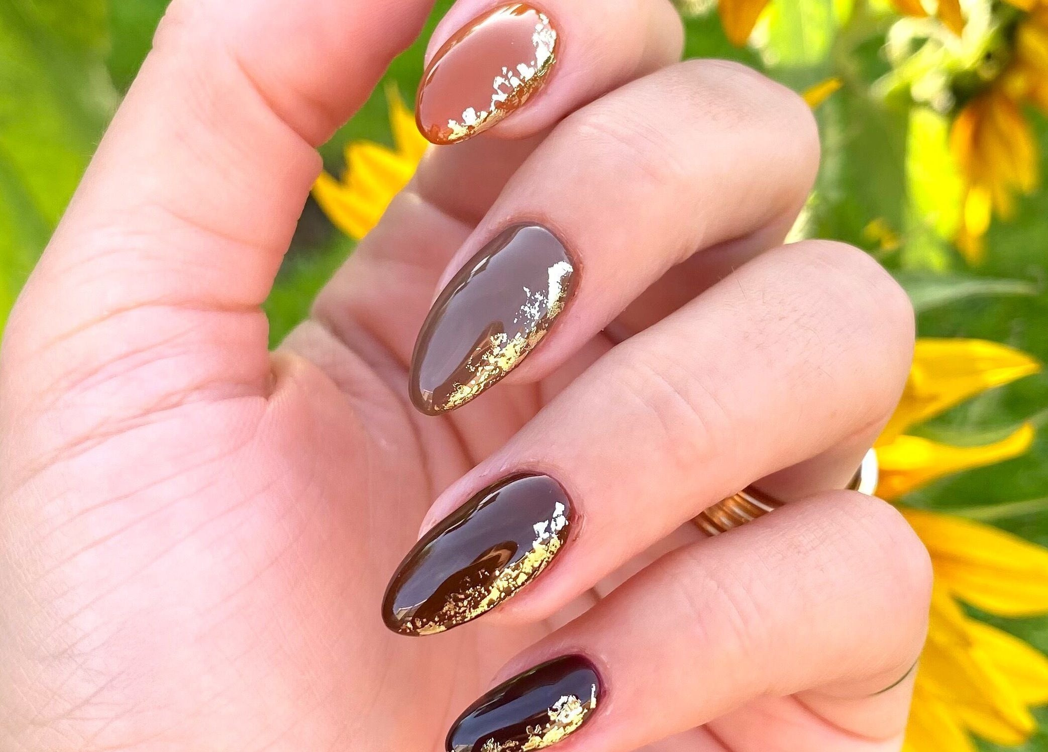 Elegant gold-accented manicure at AP Beauty MK, Towcester, England, GB, with vibrant natural backdrop.