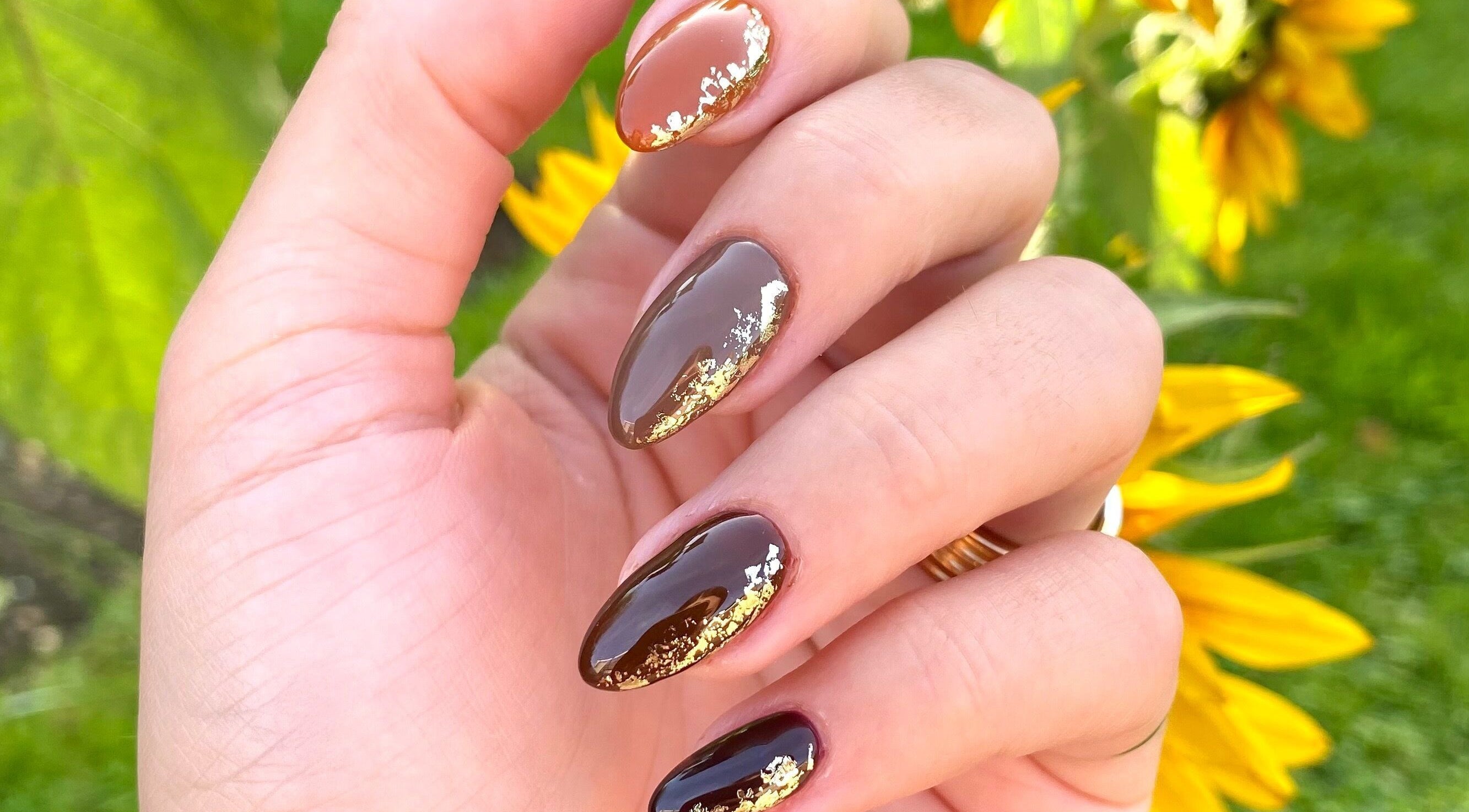 Elegant gold-accented manicure at AP Beauty MK, Towcester, England, GB, with vibrant natural backdrop.