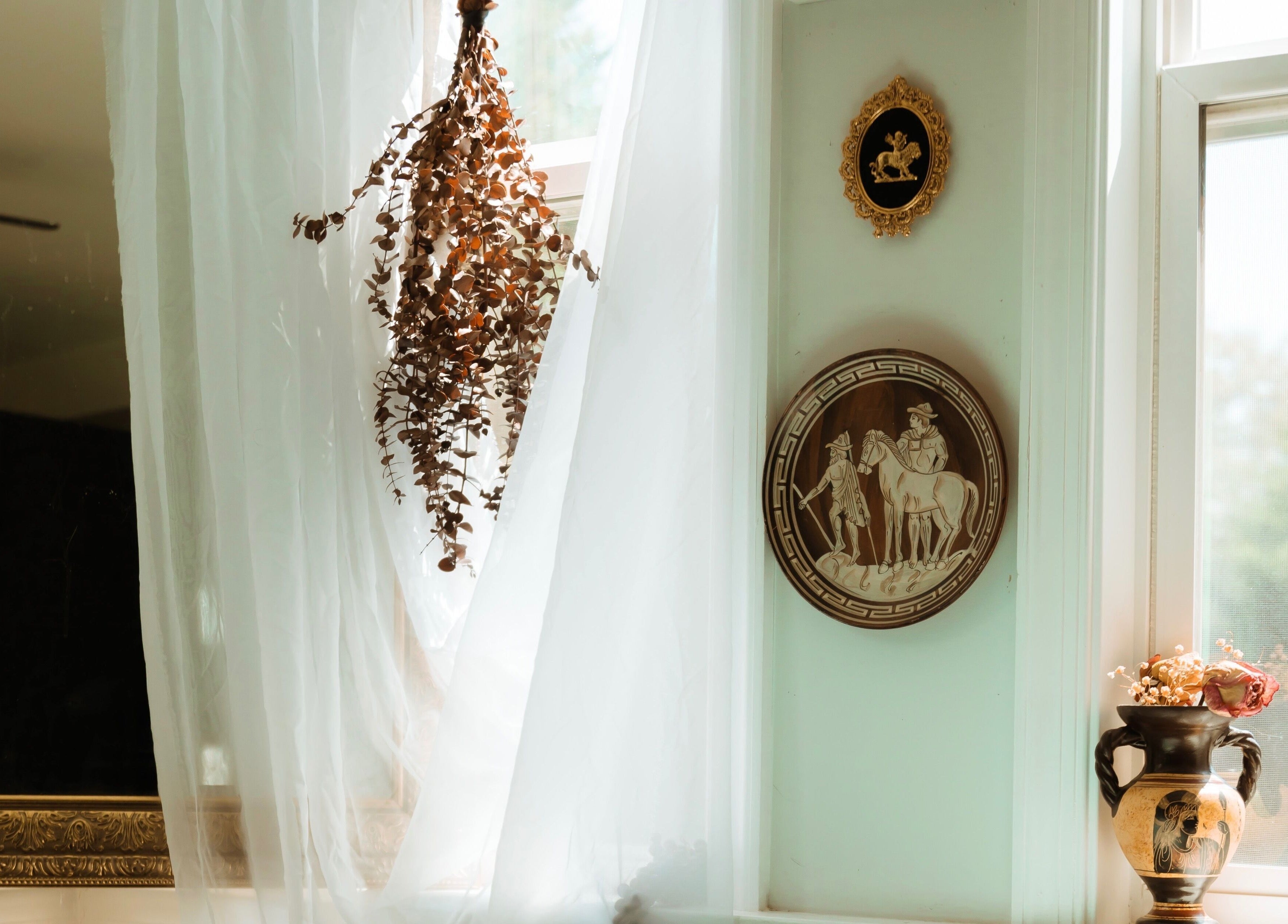 Elegant decor at Hands of Chiron, Baltimore, Maryland, US featuring soft curtains and vintage wall art.
