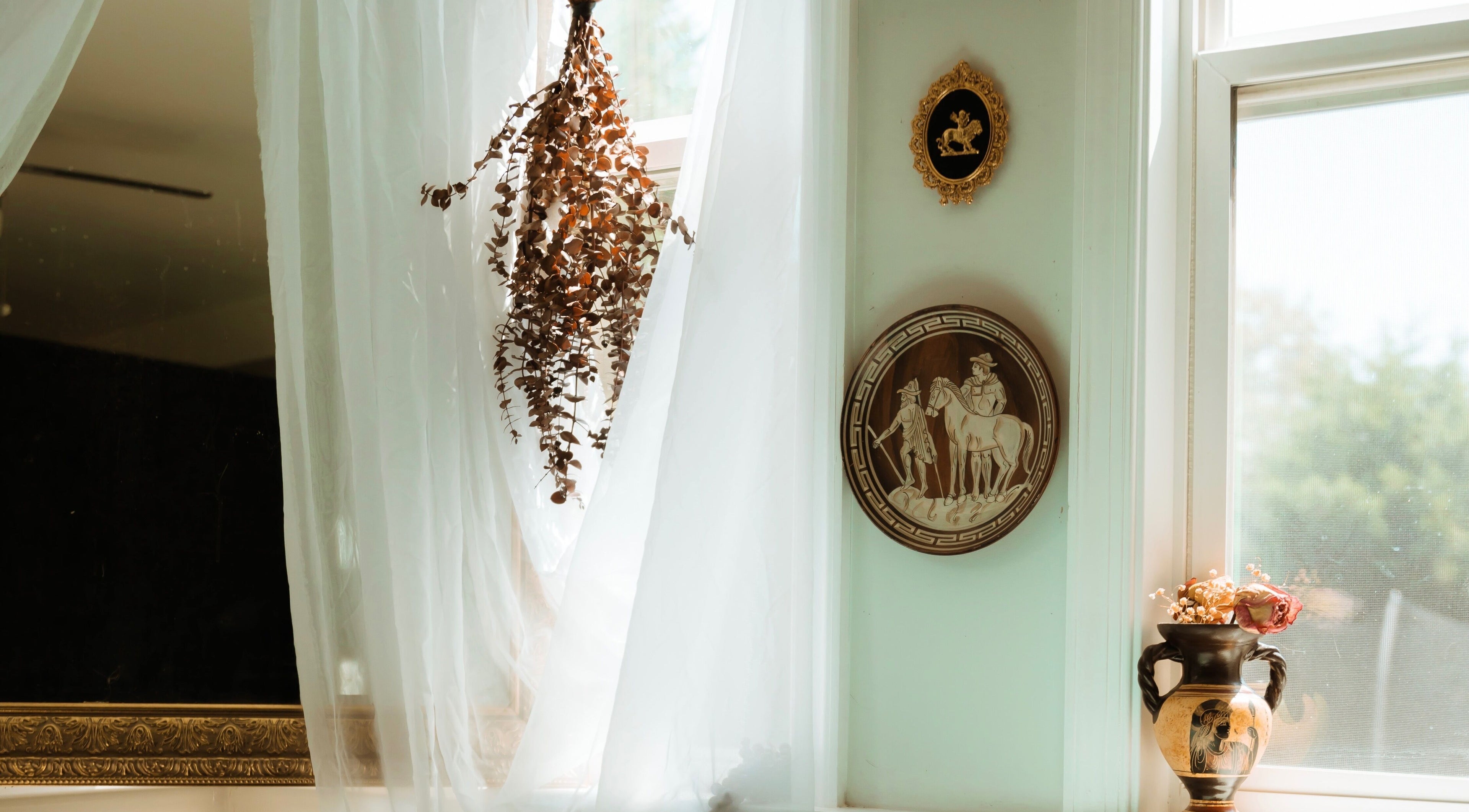 Elegant decor at Hands of Chiron, Baltimore, Maryland, US featuring soft curtains and vintage wall art.