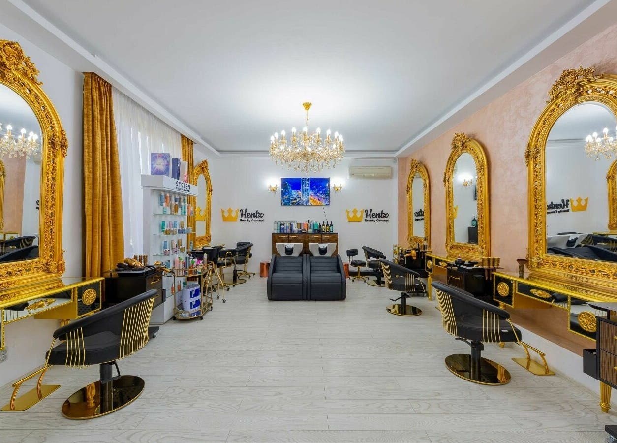 Interior luxos al salonului Hentz Beauty Concept din Voluntari, Județul Ilfov, RO, cu oglinzi aurii și candelabru elegant.