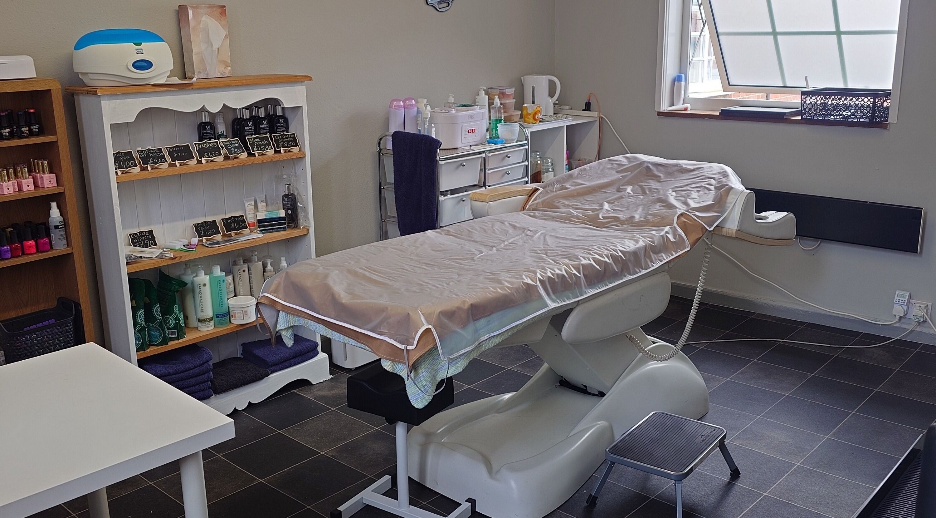 A tranquil treatment room at By Lily Beauty And Hair in Dereham, England, GB featuring a massage bed and products.