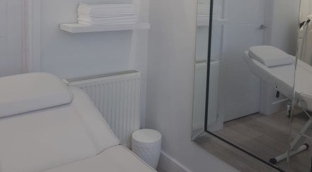 Calming treatment room at Sculpted & Skin, Ware, England, GB with a white massage bed and neatly stacked towels.
