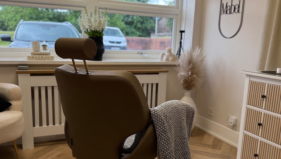 Stylish interior of Mabel Studio in Blantyre, Scotland. A cozy chair faces a bright window with lush greenery outside.