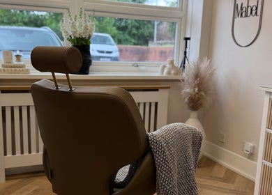 Stylish interior of Mabel Studio in Blantyre, Scotland. A cozy chair faces a bright window with lush greenery outside.