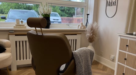 Stylish interior of Mabel Studio in Blantyre, Scotland. A cozy chair faces a bright window with lush greenery outside.