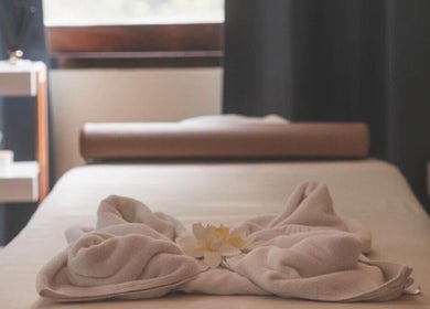 Massage table with towels and flower at Ozen Home Spa Cafe, Pattaya, Chon Buri, TH, offering a serene ambiance.