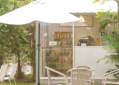 Outdoor seating with umbrella at Ozen Home Spa Cafe, Pattaya, Chon Buri, TH. Relax in this lush, green oasis.