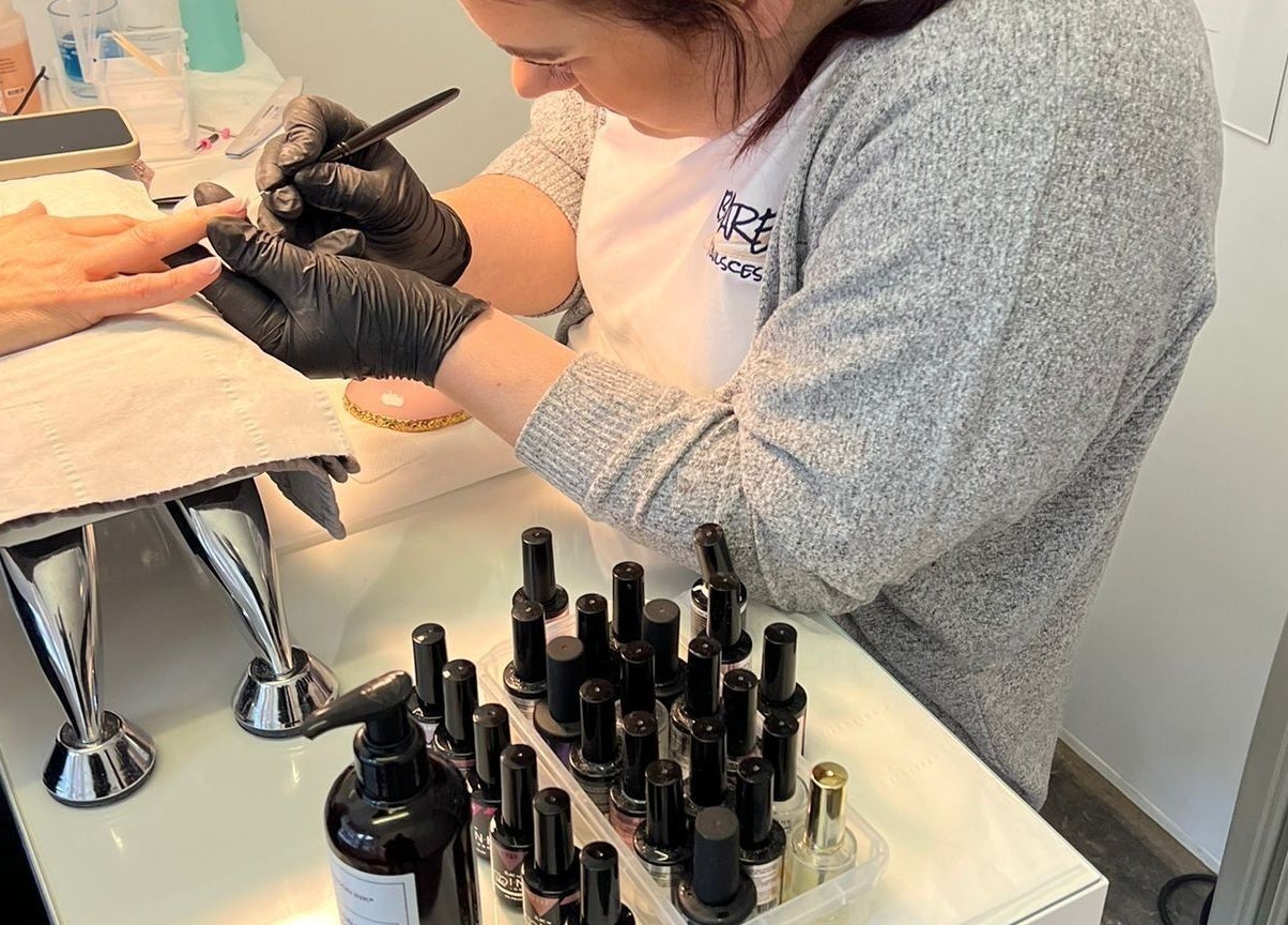 Professional nail artist at Bare Nailscessity @ Hidden Beauty, East Cowes, England, GB perfecting a manicure.