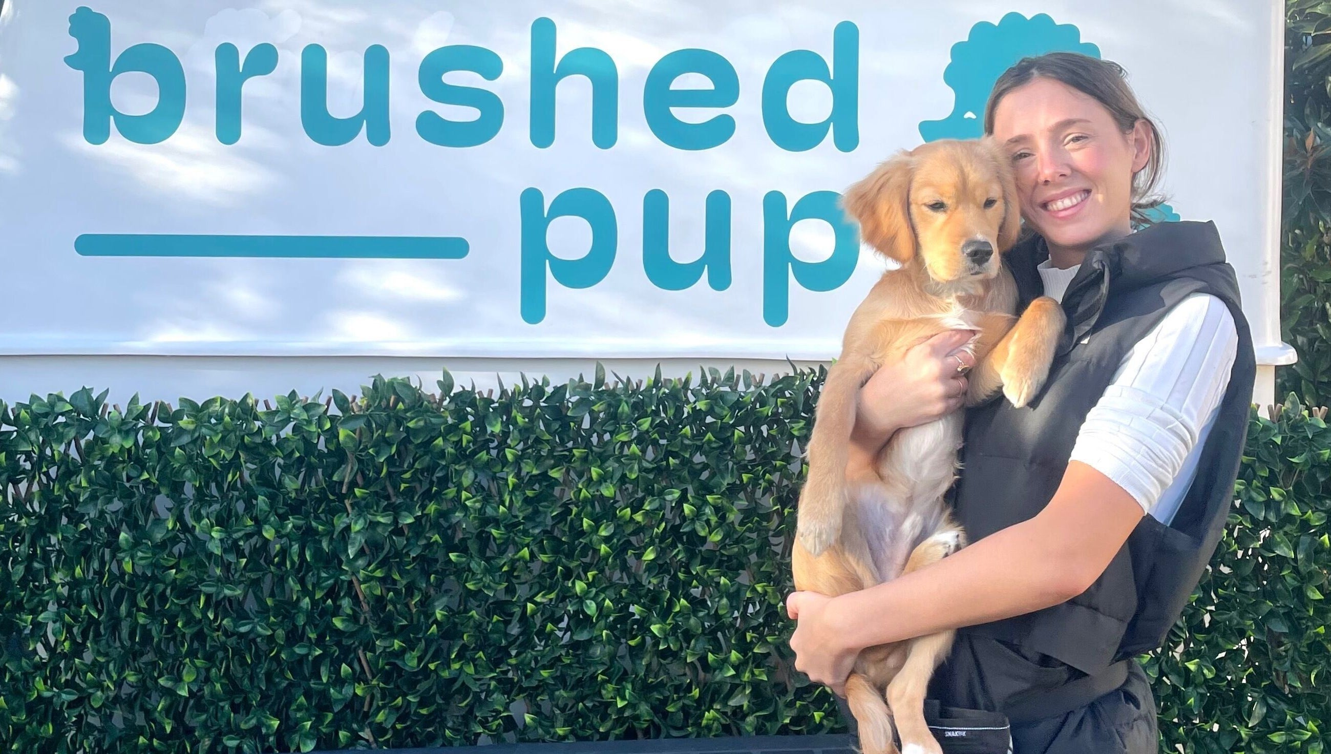 Brushed Pup Grooming in Albion Park Rail, New South Wales, AU, features a friendly groomer holding a happy dog.