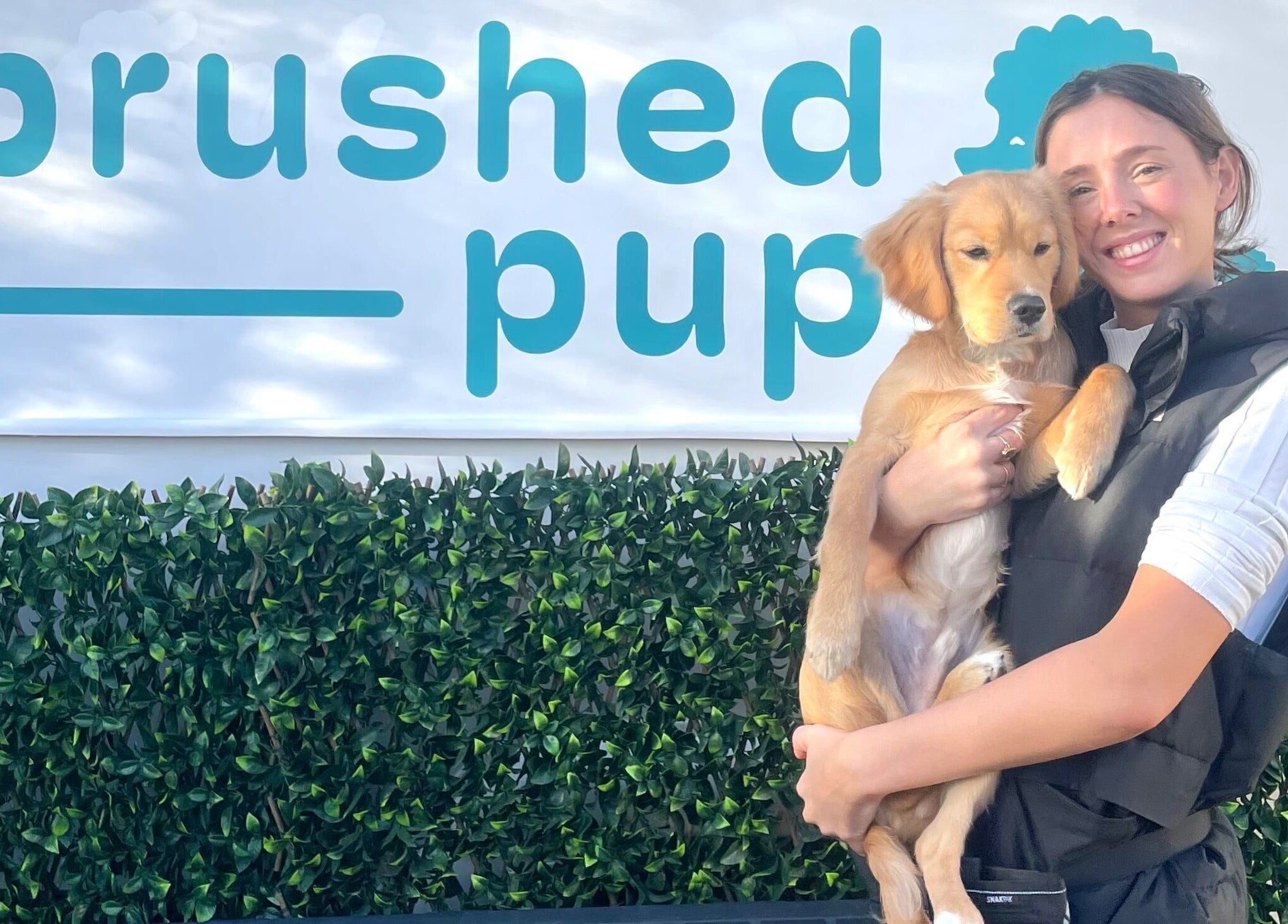 Brushed Pup Grooming in Albion Park Rail, New South Wales, AU, features a friendly groomer holding a happy dog.