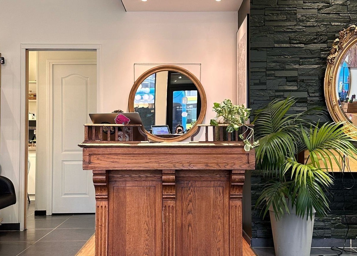 Réception en bois de LOFT HAIR à Reims, Grand Est, FR, avec miroir circulaire et plantes vertes.