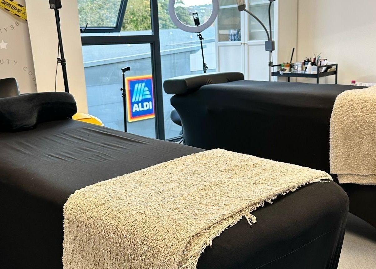 Two black spa beds with beige towels at Millzbeauty, High Wycombe, England, GB, near a large window.
