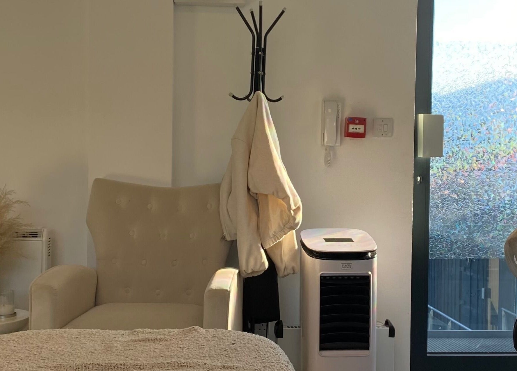 Elegant chair by the window at Millzbeauty, High Wycombe, England, GB, with coat rack and modern decor.