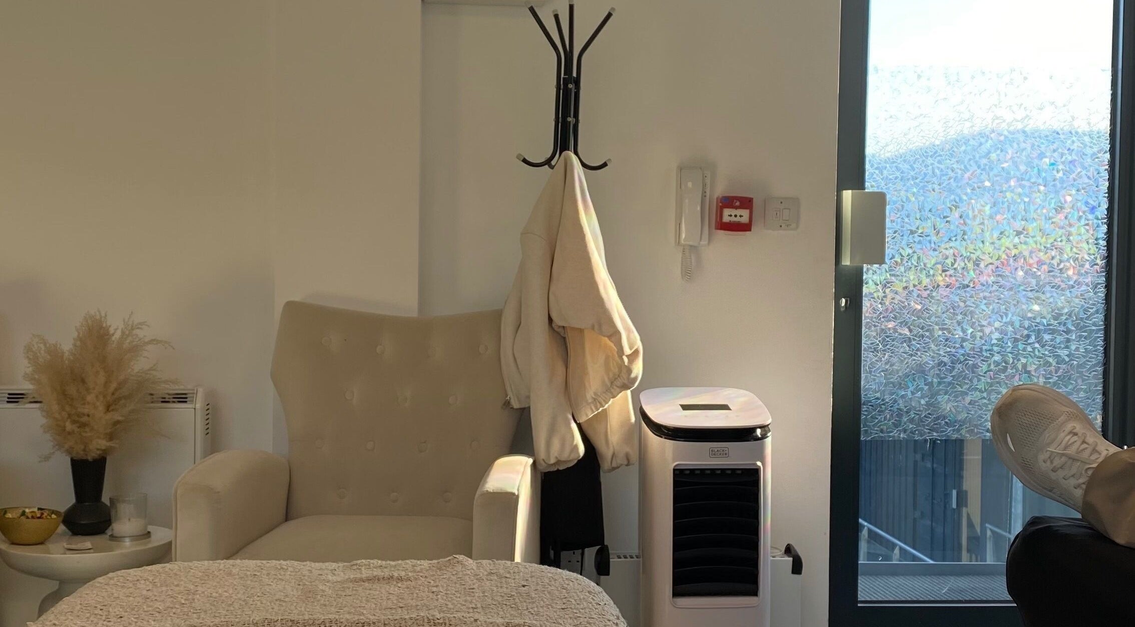 Elegant chair by the window at Millzbeauty, High Wycombe, England, GB, with coat rack and modern decor.