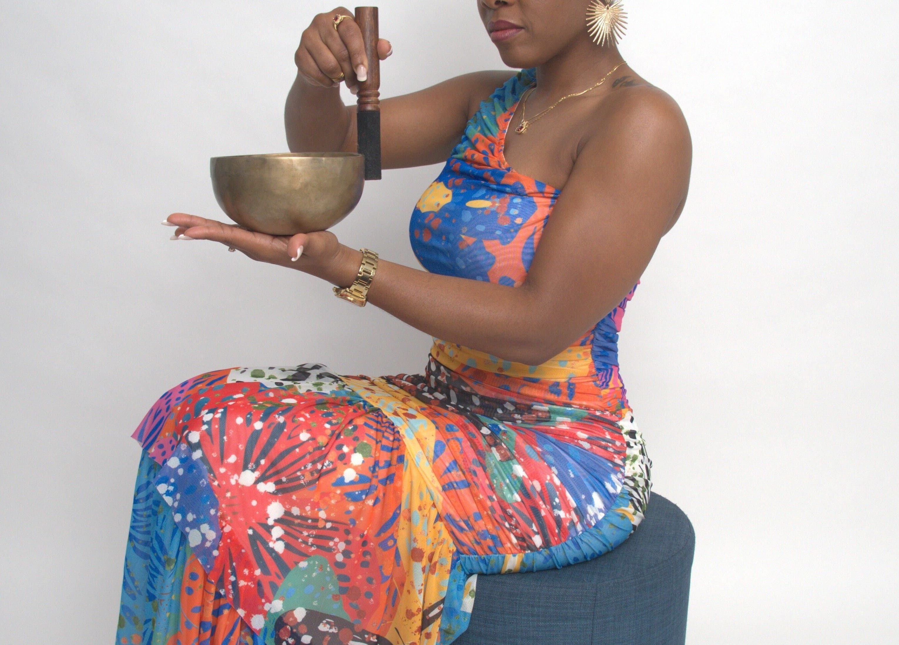 A woman uses a singing bowl at Black Oasis Luxury Mind & Body in Conyers, Georgia, US. Vibrant spiritual practice.