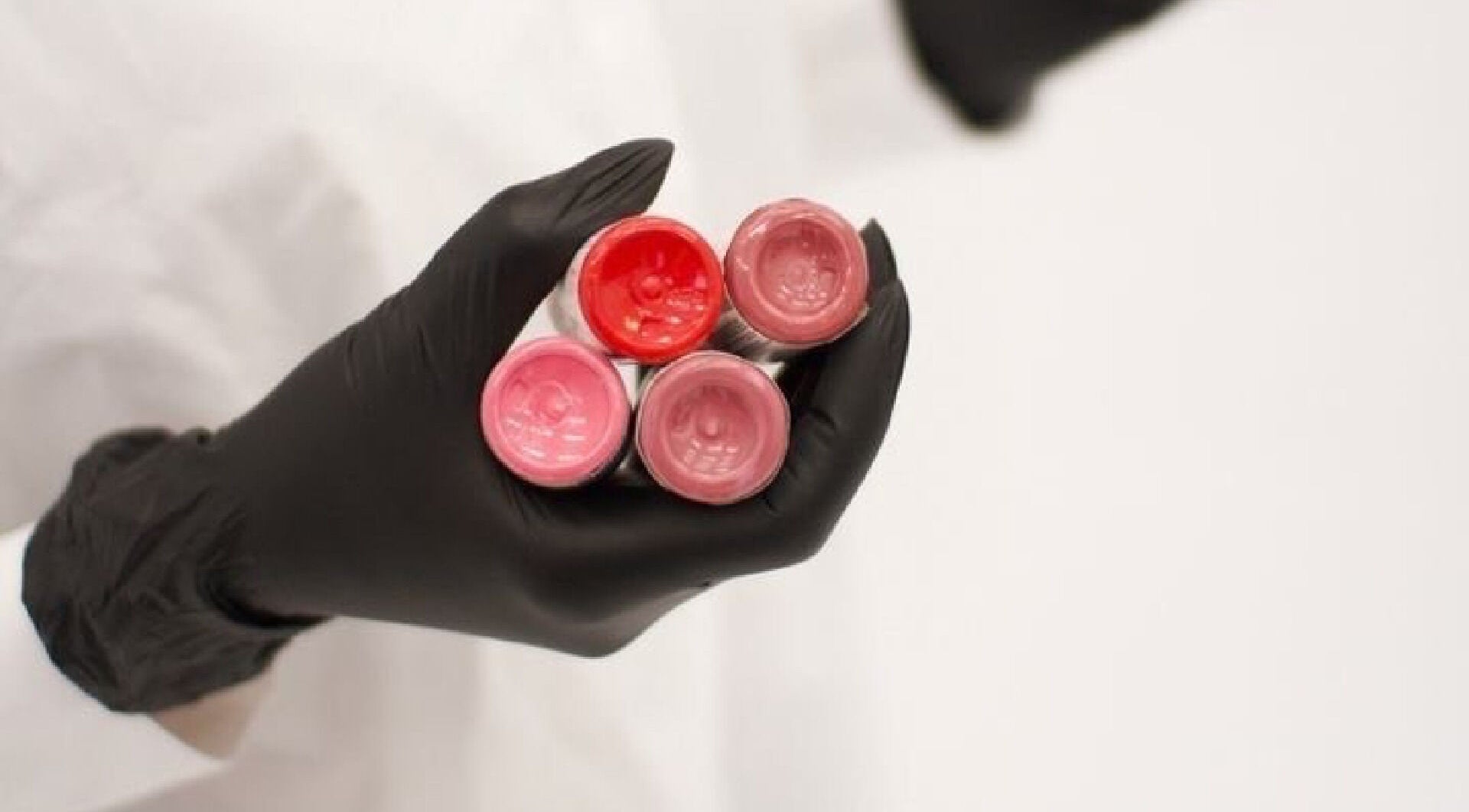 Hand in glove holding vibrant lip colors at Basildon Essex (ALAMODE AESTHETICS), Basildon, England, GB.