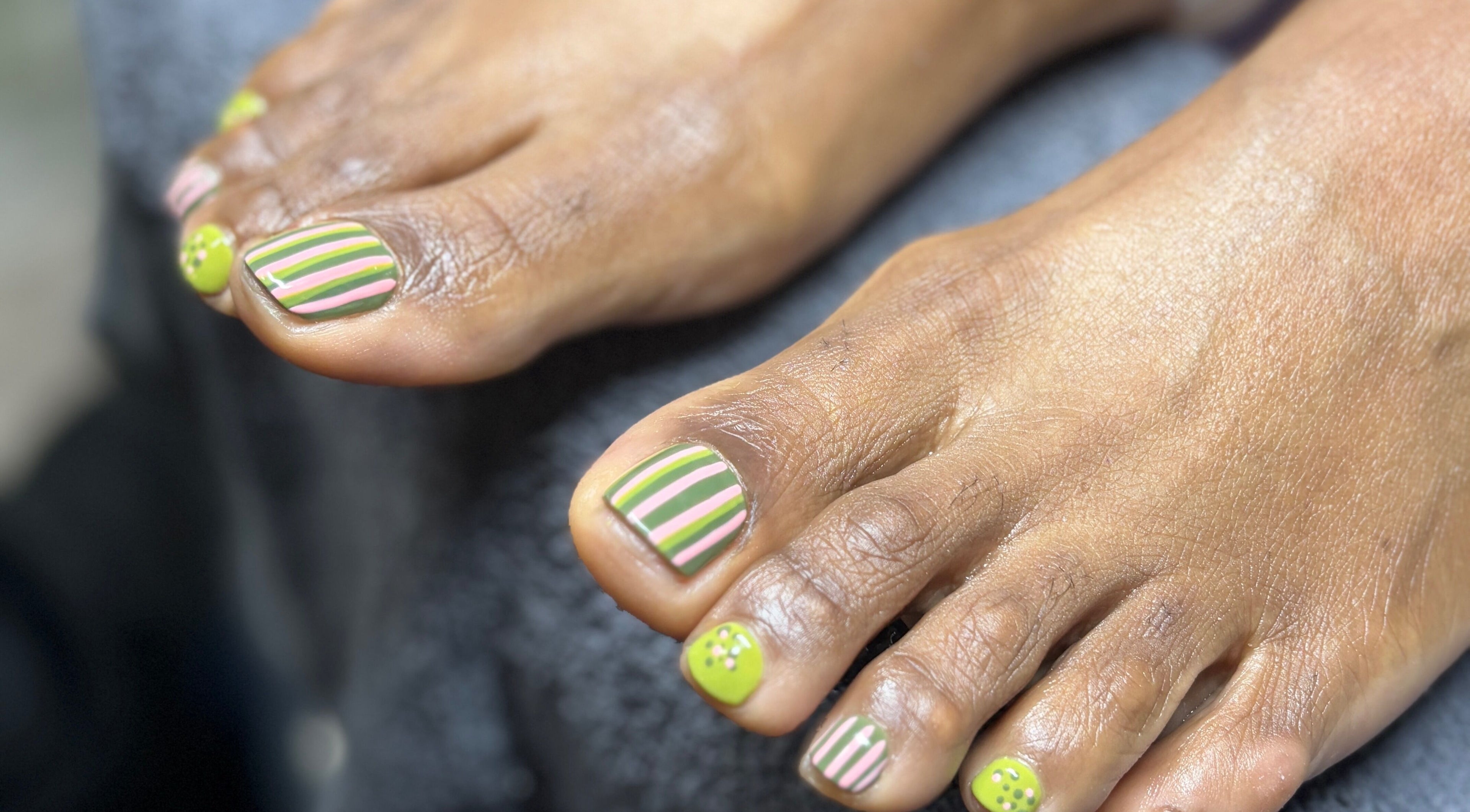 Colorful striped nail art on toes at Nubian Nails, Morrow, Georgia, US.