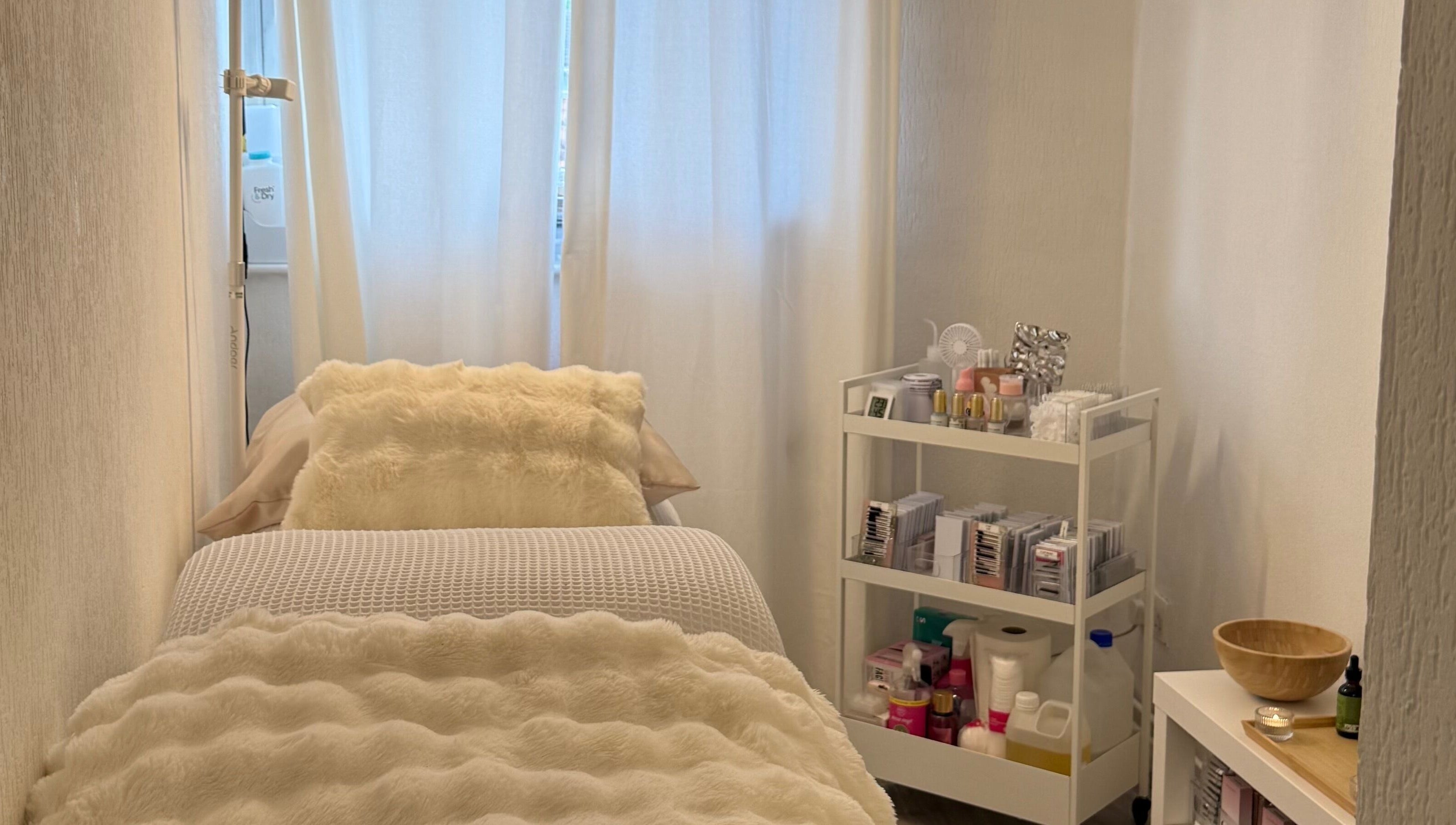 Relaxing treatment room at By KB in Manchester, England, GB, featuring a plush bed and beauty products.