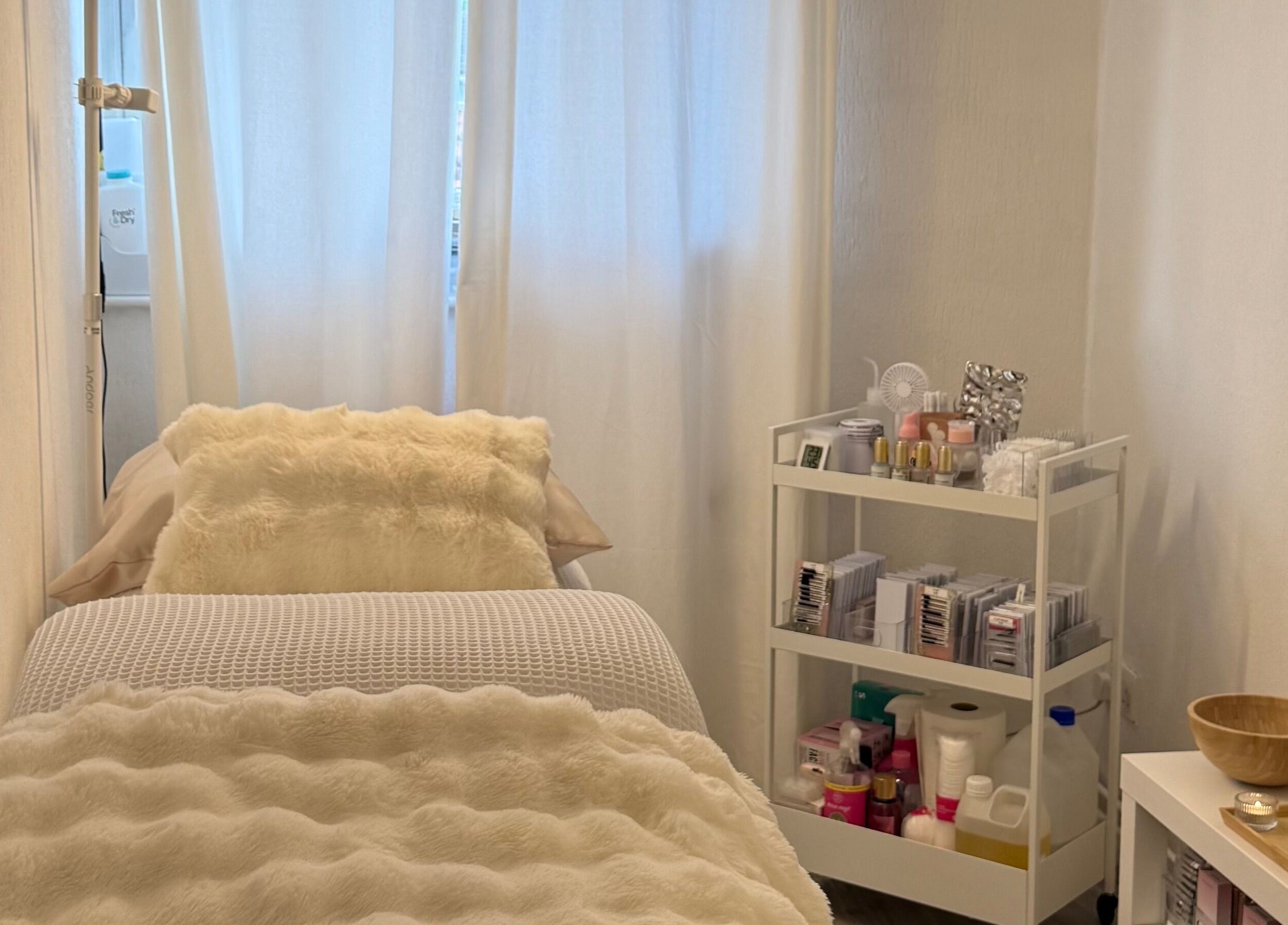 Relaxing treatment room at By KB in Manchester, England, GB, featuring a plush bed and beauty products.