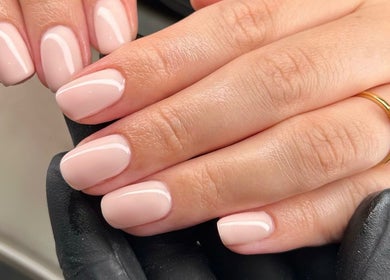 Elegant manicured nails at MD Nails in Bishop's Stortford, England, GB. Soft pink polish and gold ring accent.