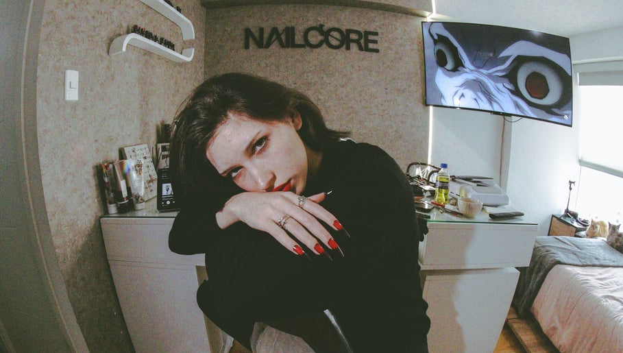 Interior del Nailcore® Studio en Lima, Provincia De Lima, PE, con una clienta mostrando uñas rojas.