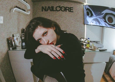 Interior del Nailcore® Studio en Lima, Provincia De Lima, PE, con una clienta mostrando uñas rojas.