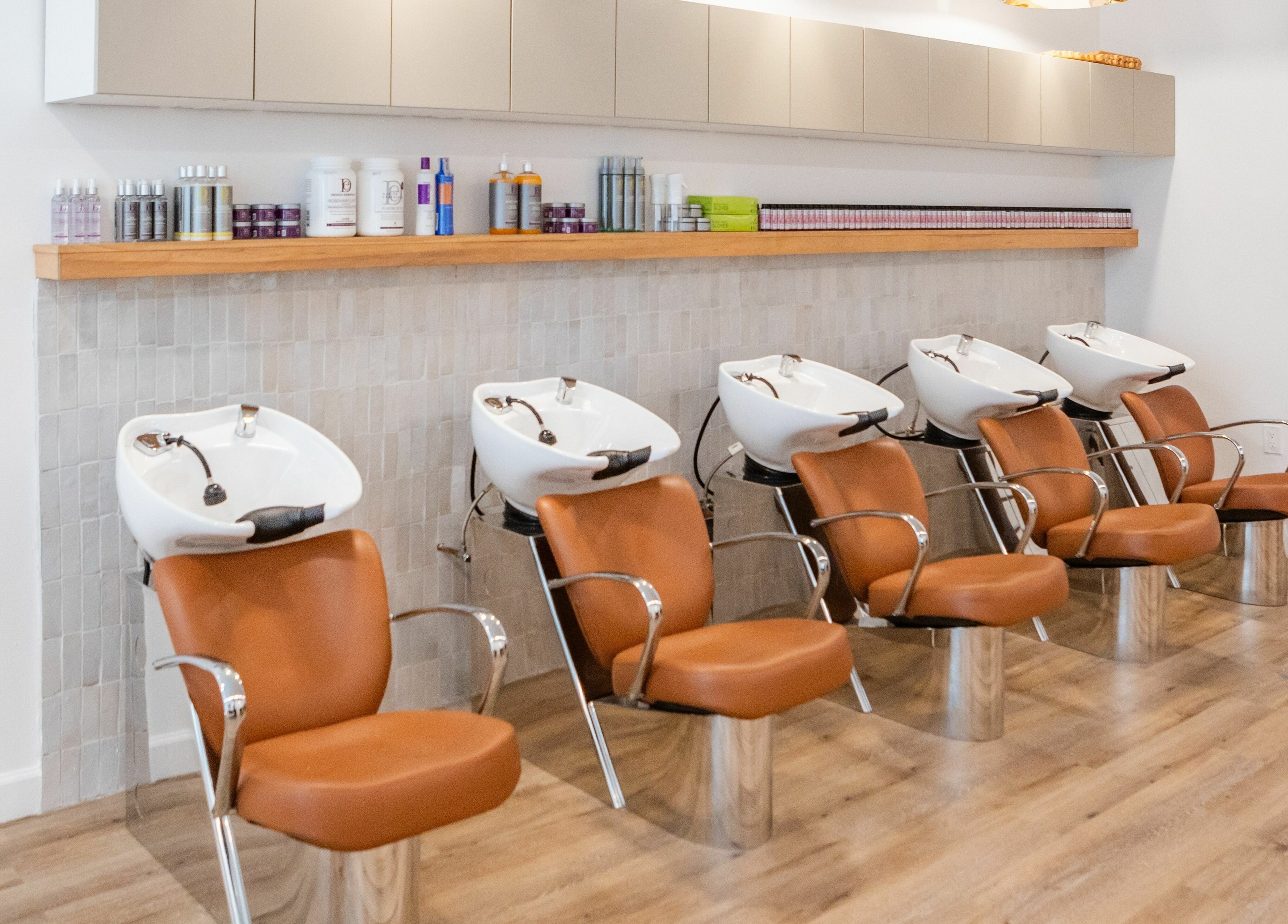 Chic wash station setup at TASH BLAQUE, New York, New York, US. Modern brown chairs and sinks in well-lit salon.