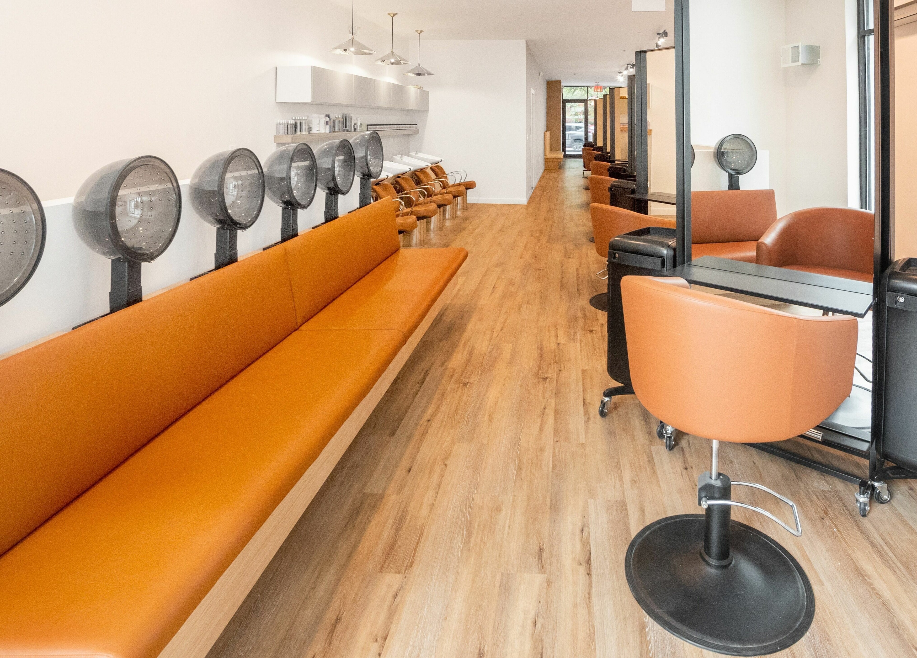 Modern salon interior at TASH BLAQUE, New York, New York, US, featuring stylish seating and hair dryers.
