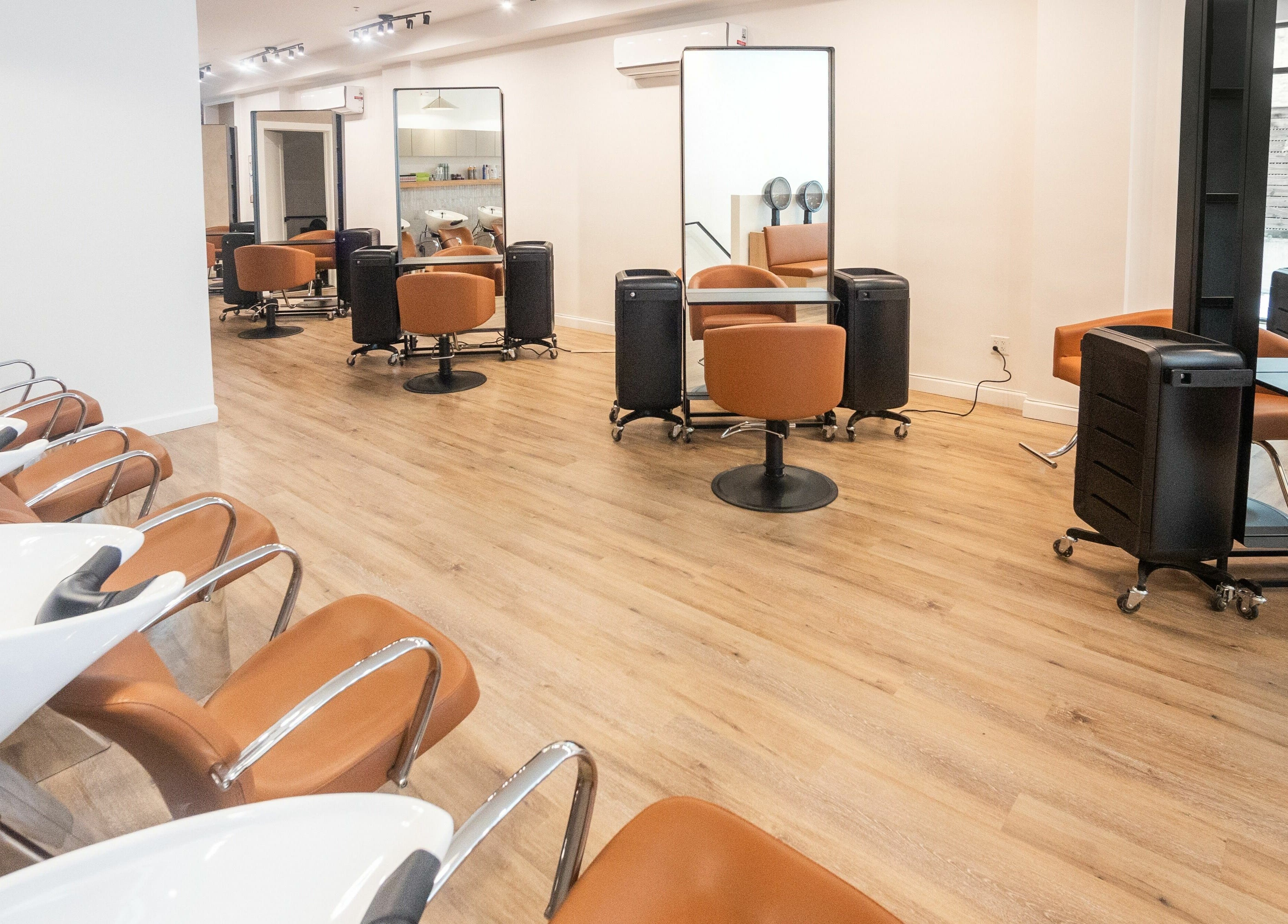 Spacious salon interior at TASH BLAQUE, New York, New York, US with modern styling stations and washbasins.