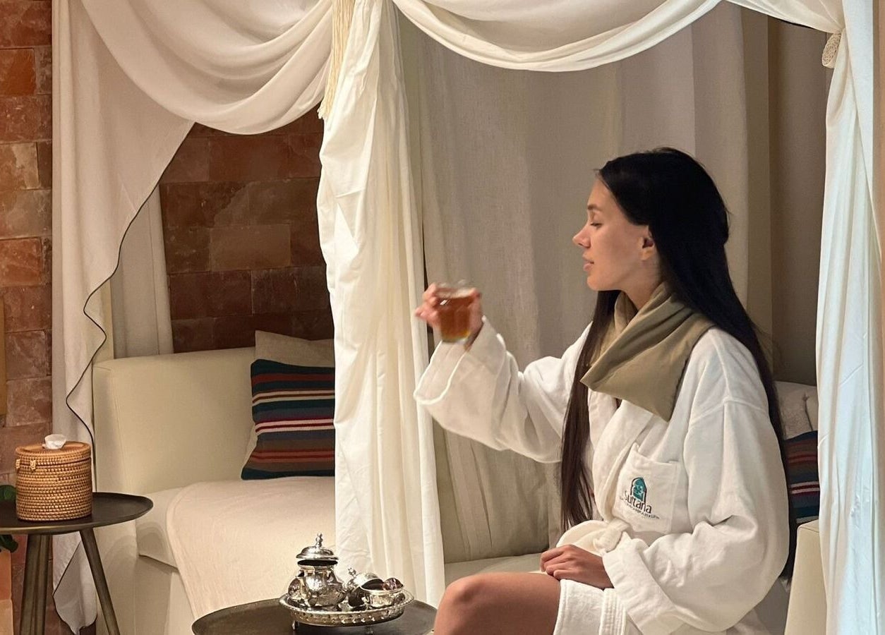 Woman enjoying tea in a cozy spa setting at Sultana Spa LLC, Dubai, AE.