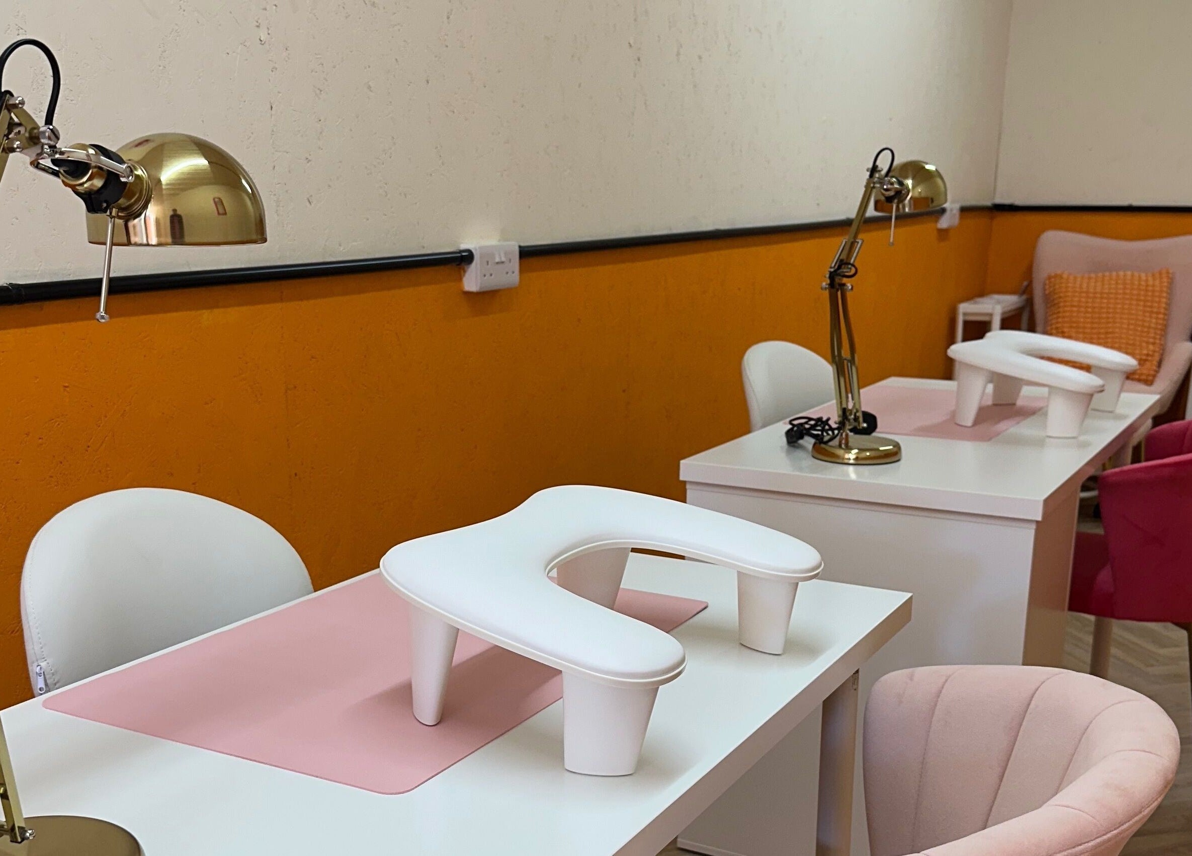 So Gel Studio's modern nail stations with plush pink chairs in Bristol, England, GB accent the elegant orange decor.
