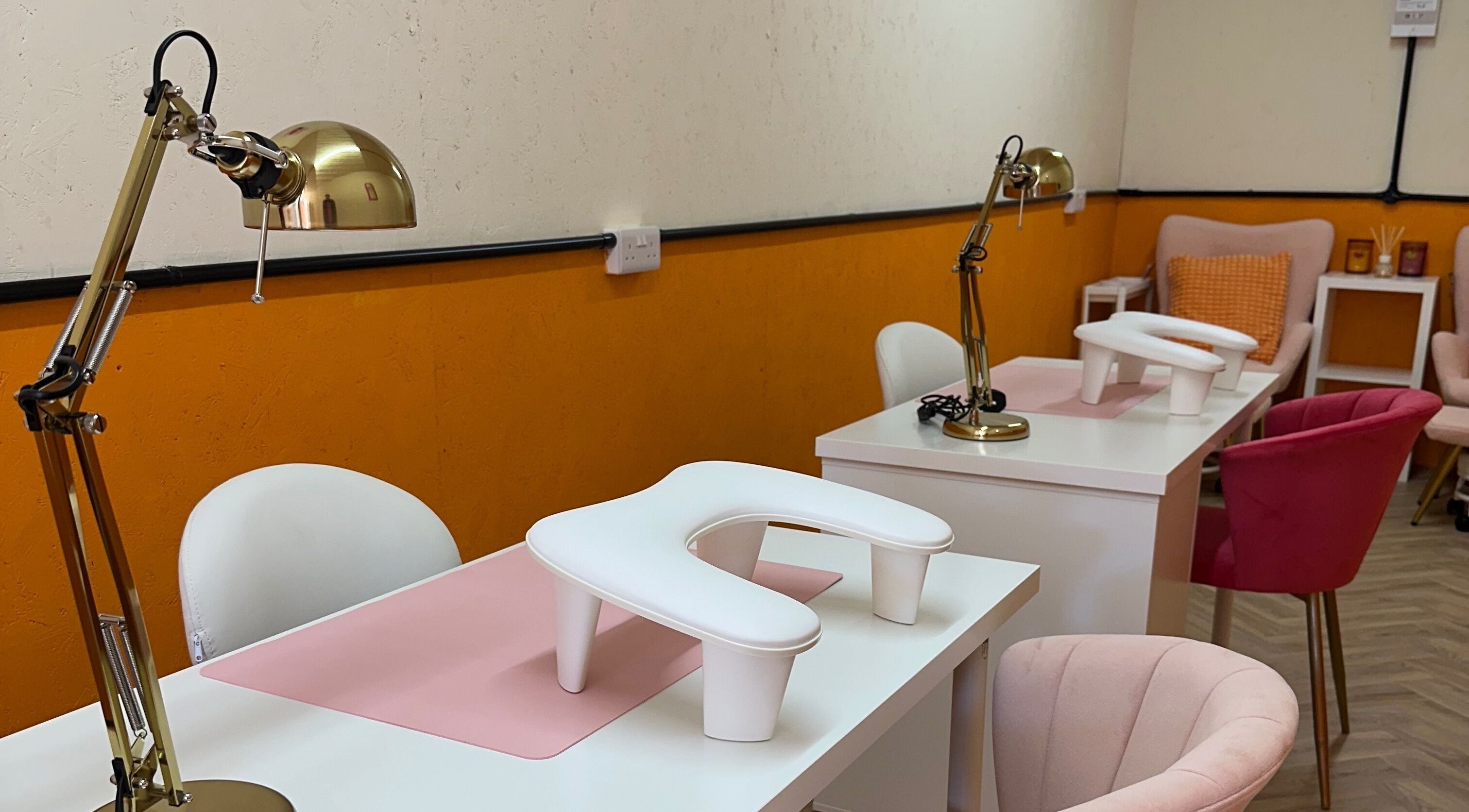 So Gel Studio's modern nail stations with plush pink chairs in Bristol, England, GB accent the elegant orange decor.