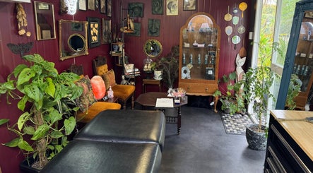 Inviting interior of Pin Cushion Piercing in Buckland, Waikato, NZ, featuring vintage decor and vibrant plants.