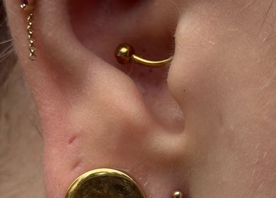 Stylish gold ear piercing from Pin Cushion Piercing in Buckland, Waikato, NZ showcases unique jewelry.
