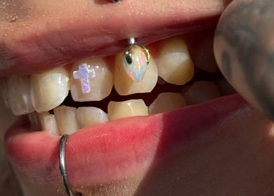 Unique tooth gem design at Pin Cushion Piercing, Buckland, Waikato, NZ, showcasing opal and cross details.
