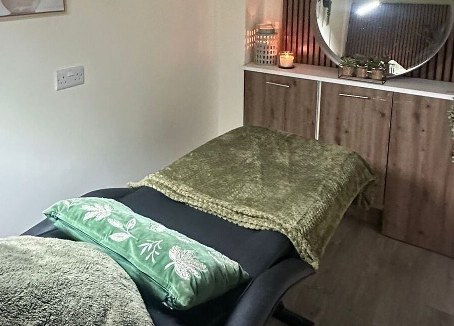 A serene massage room at Sage Beauty By Charelle, Kilmacolm, Scotland, GB with a cozy green blanket and candles.