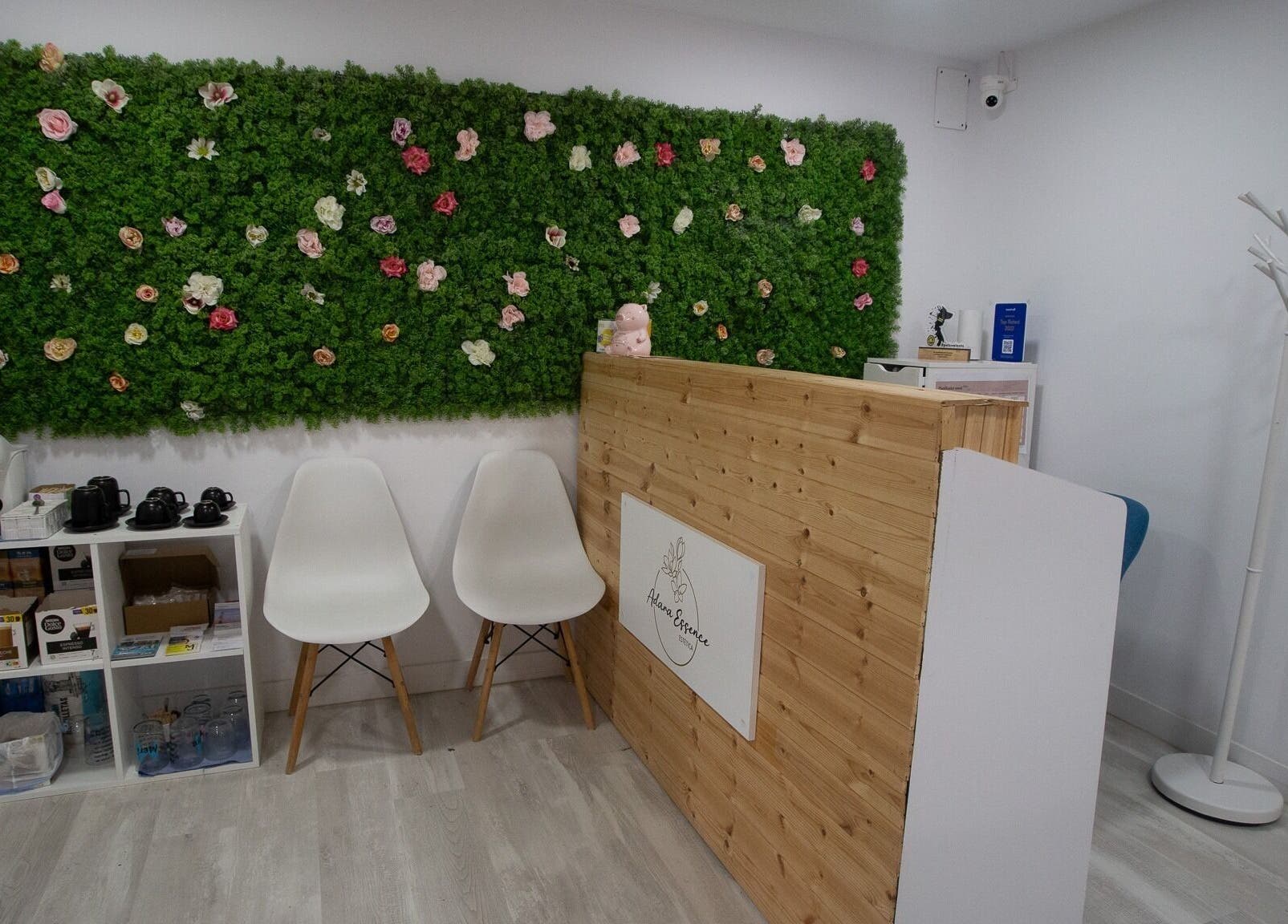 Recepción de Adara Essence Estetica en Sant Andreu Salou, Catalunya, con pared verde y flores decorativas.