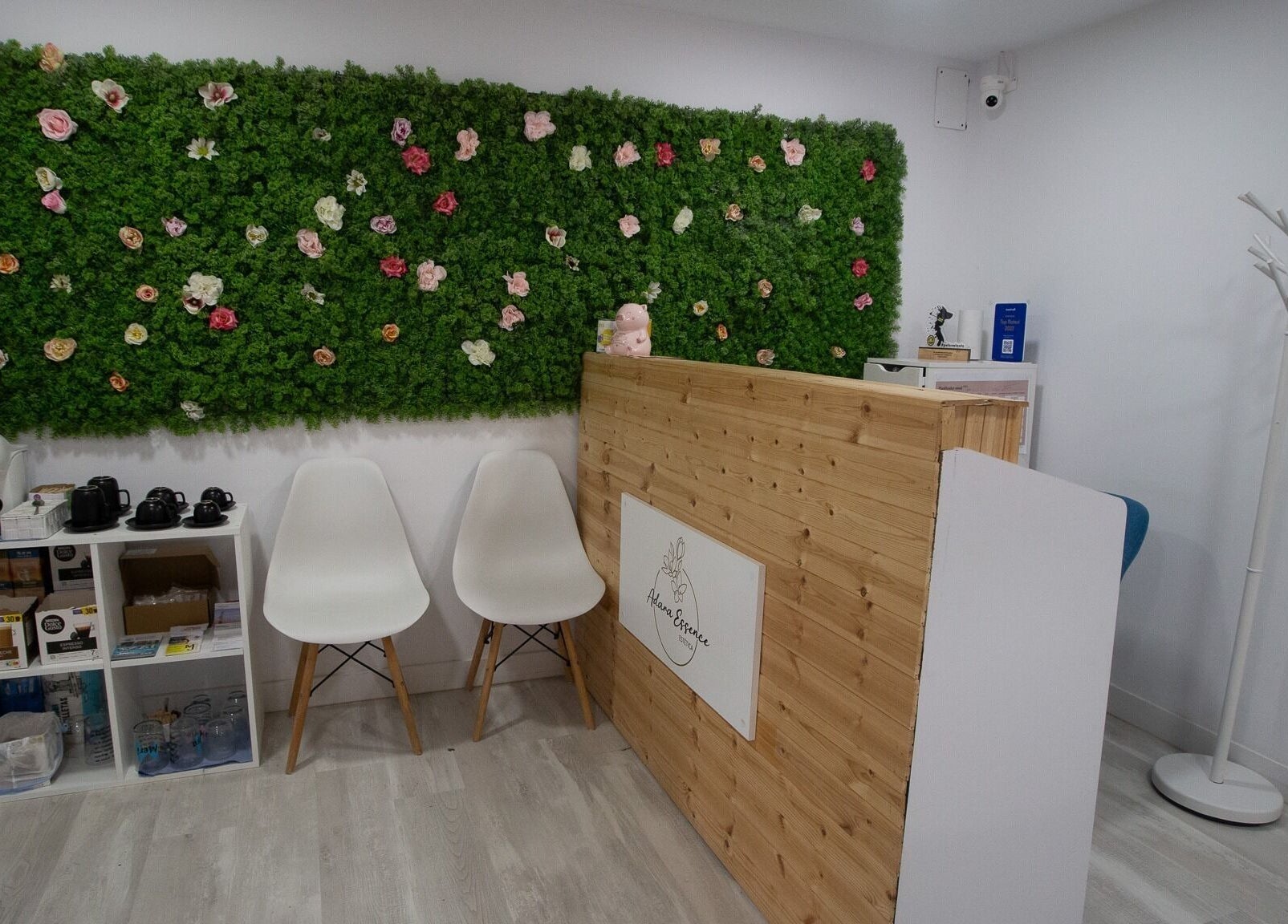 Recepción de Adara Essence Estetica en Sant Andreu Salou, Catalunya, con pared verde y flores decorativas.
