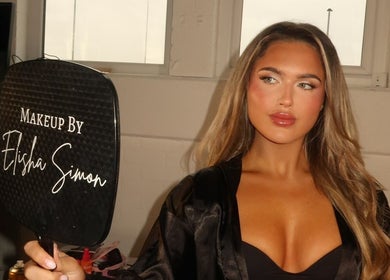 Woman holding mirror with 'Makeup by Elisha Simon' in Northampton, England, GB showcasing exquisite makeup.