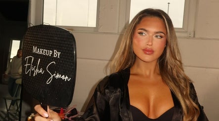 Woman holding mirror with 'Makeup by Elisha Simon' in Northampton, England, GB showcasing exquisite makeup.