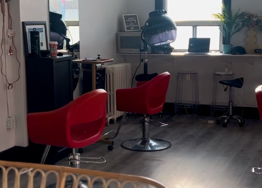 Modern salon interior at Curls by Jenn, Toronto, Ontario, CA with stylish red chairs and sleek design.