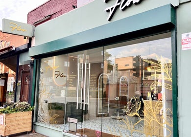 Exterior view of Mami Yaba Salon in London, England, GB, showing stylish glass facade and floral designs.