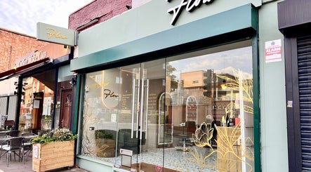 Exterior view of Mami Yaba Salon in London, England, GB, showing stylish glass facade and floral designs.