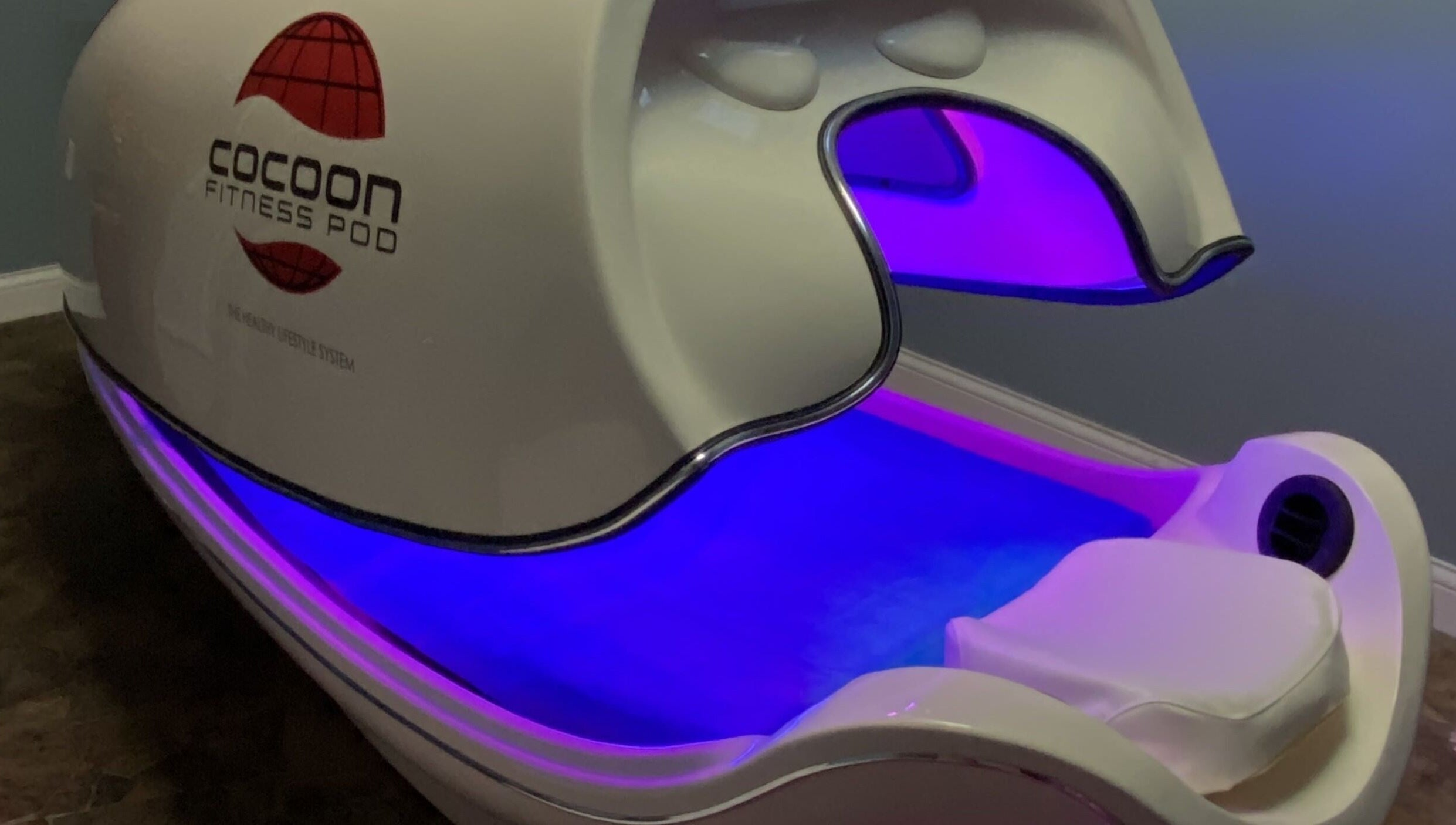 Cocoon Fitness Pod at Inside Out Infrared Wellness - Cairns in Aeroglen, Queensland, AU, glowing with purple light.