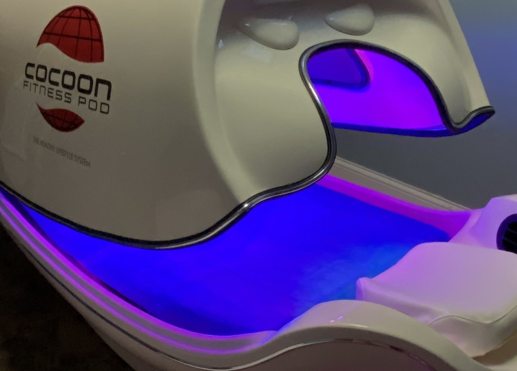 Cocoon Fitness Pod at Inside Out Infrared Wellness - Cairns in Aeroglen, Queensland, AU, glowing with purple light.