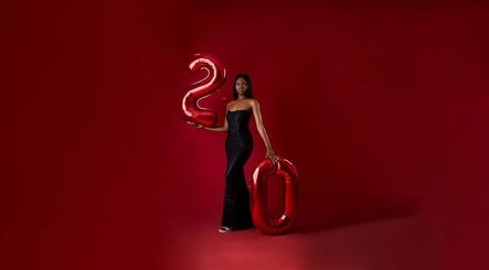 Stylish woman in black gown with balloons at Aidooklik, Accra, Greater Accra Region, GH.